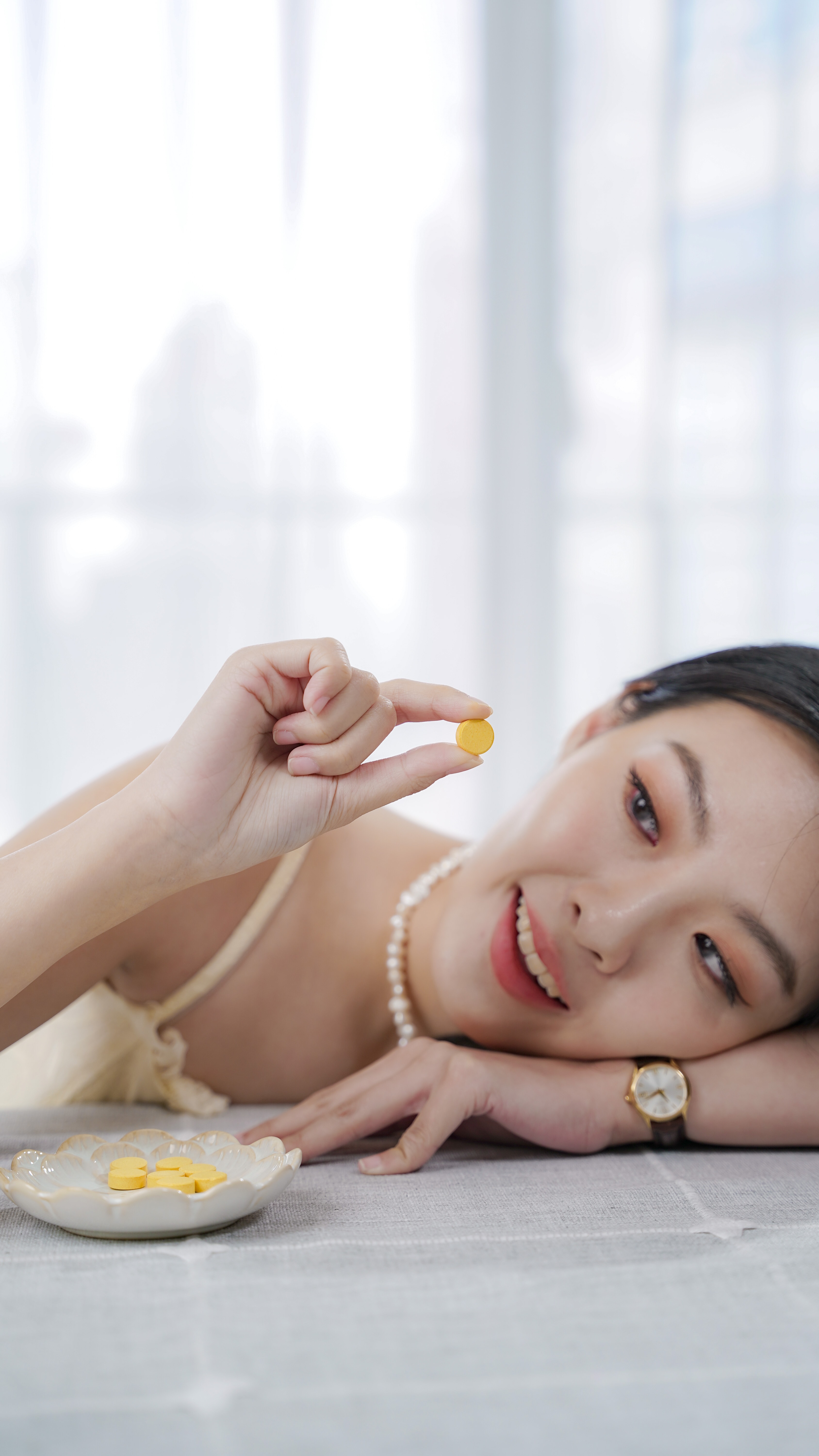 Model menunjukkan satu tablet kunyah S-Glow di antara jari.