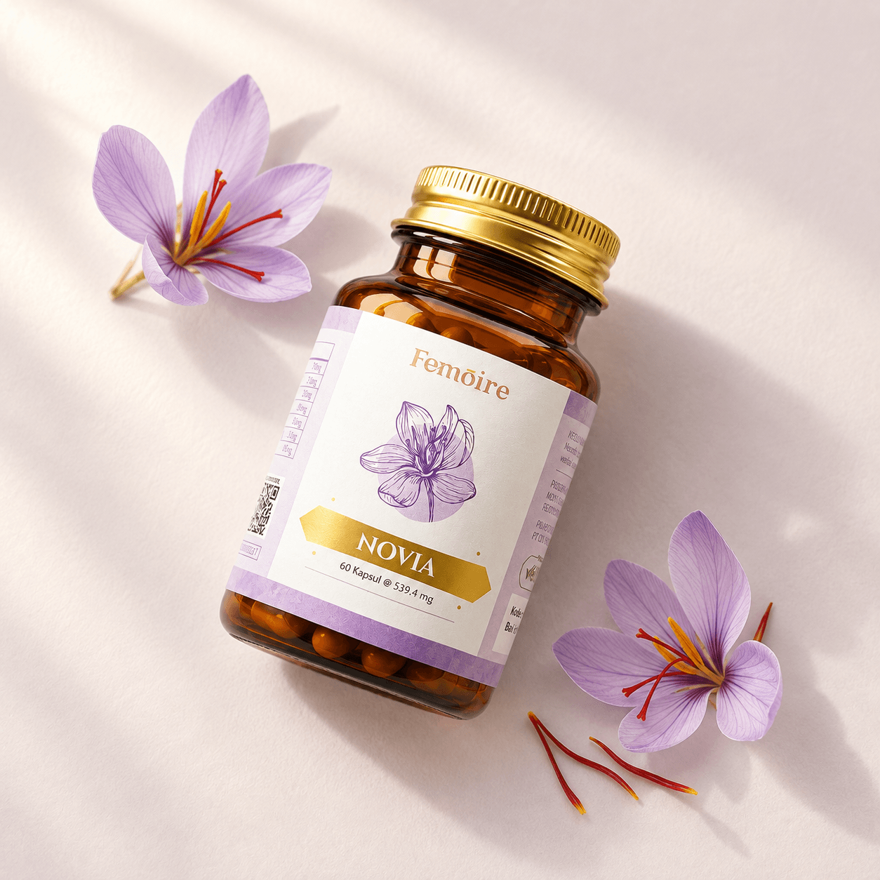 Botol Femoire Novia bertutup emas dengan bunga saffron ungu muda di atas permukaan ivory.