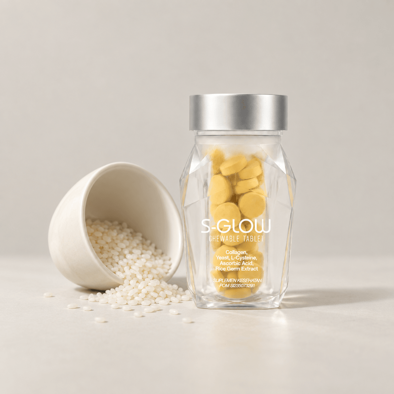 Botol S-Glow dengan mangkuk keramik ivory dan butiran beras yang mengilustrasikan bahan rice germ.