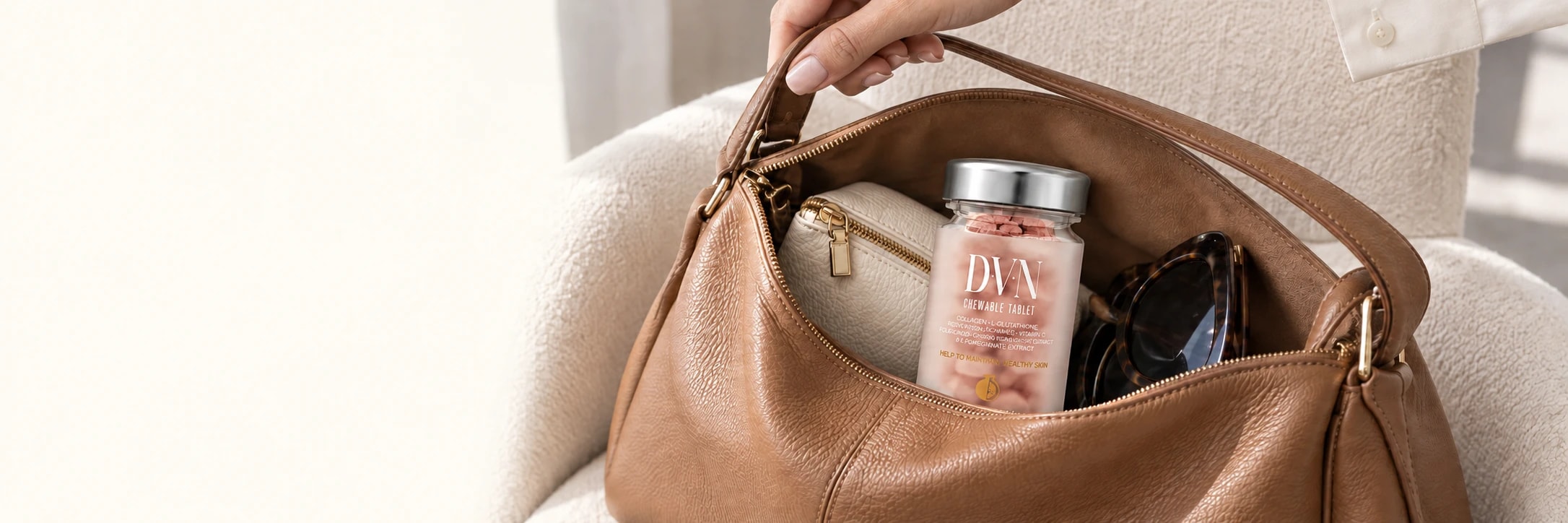 Botol DVN di dalam tas kulit tan bersama pouch dan kacamata.